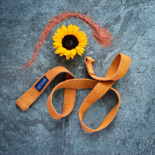 A Harvest Moon Orange Yoga Strap made from 100 percent hemp, spirals on blue grey slate.